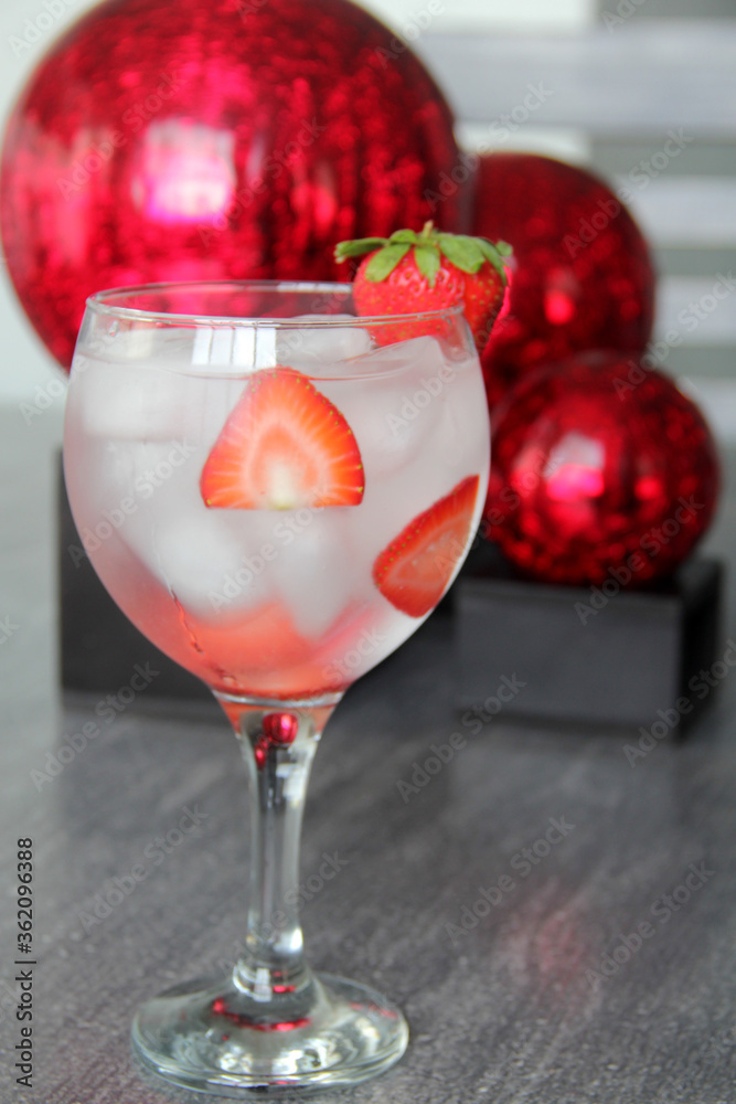 Gin tonic de fresa en mesa vintage y esferas rojas Stock Photo | Adobe Stock