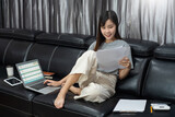 Asian woman working with laptop and document in living room remotely or work from home concept