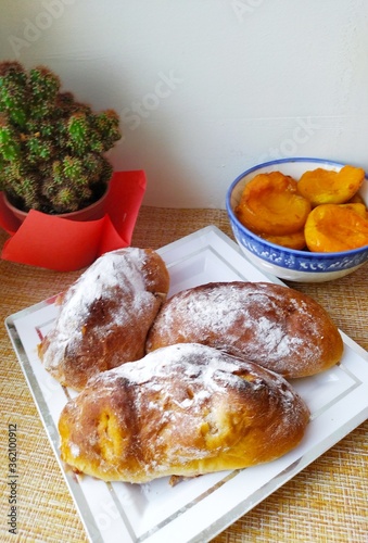 Delicious homemade cakes with powdered dugar on the table with a bowl and apricot jam and a potted flower cactus photo