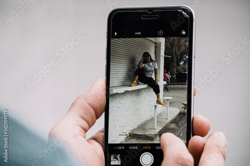 Joven hombre toma fotografía a mujer hipster con su teléfono móvil photo