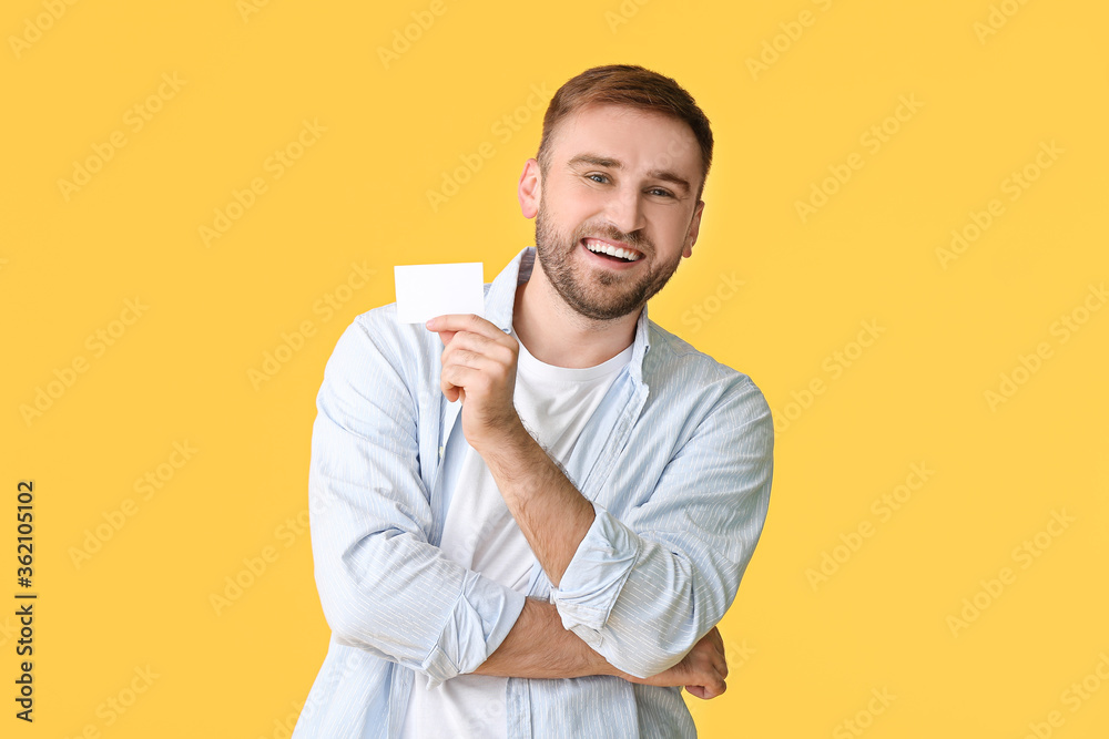 Young man with blank business card on color background