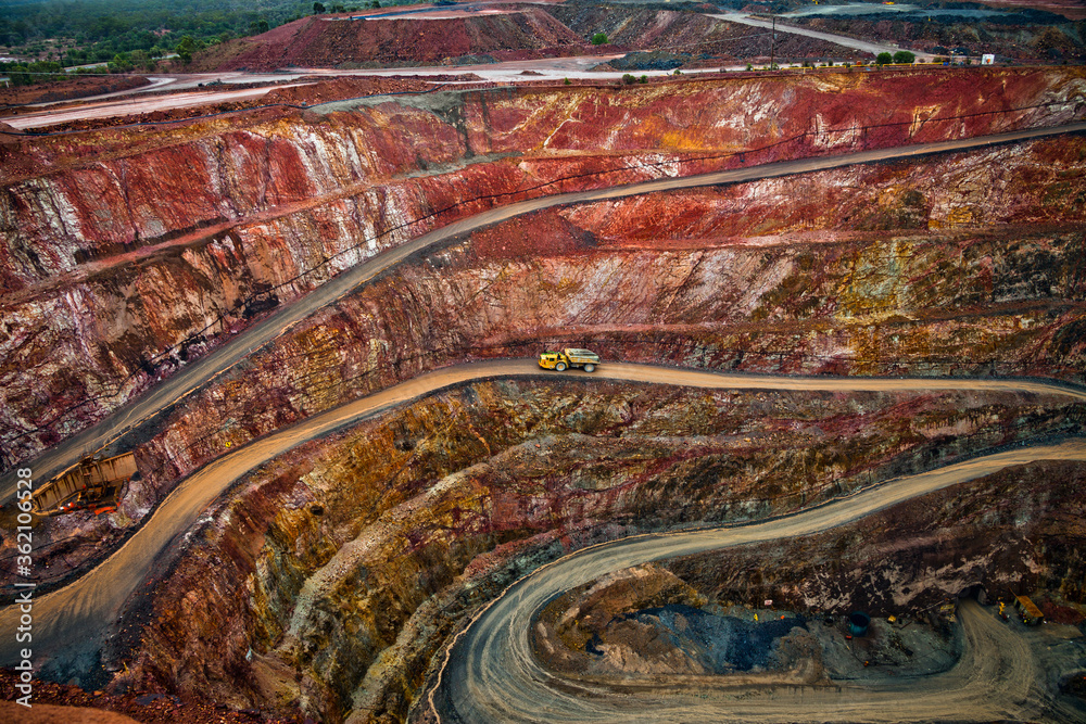 Yellow truck drives along a winding path inside an open cast mine in New South Wales, Australia.