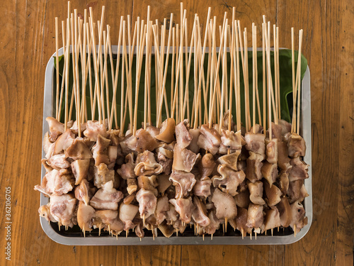 A bunch of skewered pork ears ready to be cooked on the grill. photo