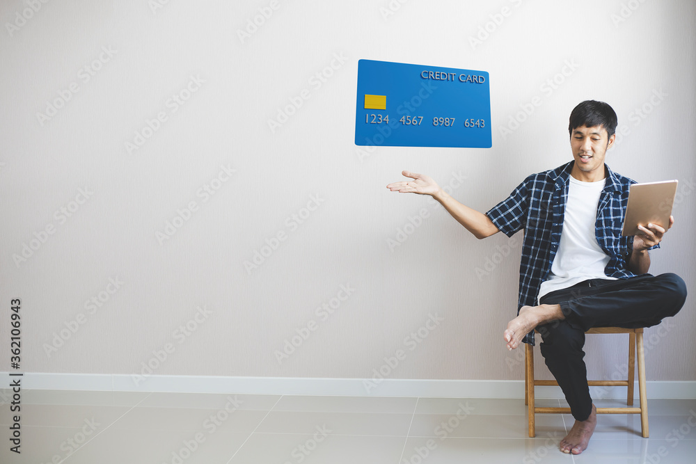 Fototapeta premium Man working on sofa in home hold smartphone with credit card for dollar shopping online.you enjoy happy freedom happiness lifestyle new normal travel During epidemic coronavirus covid-19.