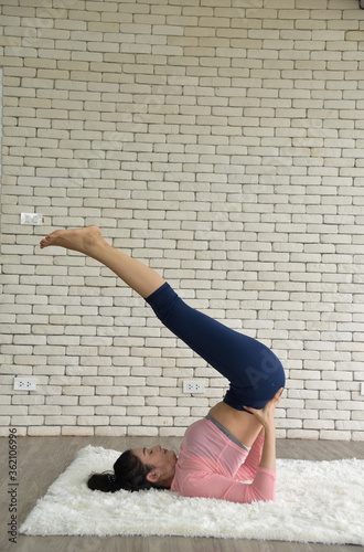 An attractive Asian woman with smiling in sportswear practicing yoga at home/Exercising for healthy lifestyle