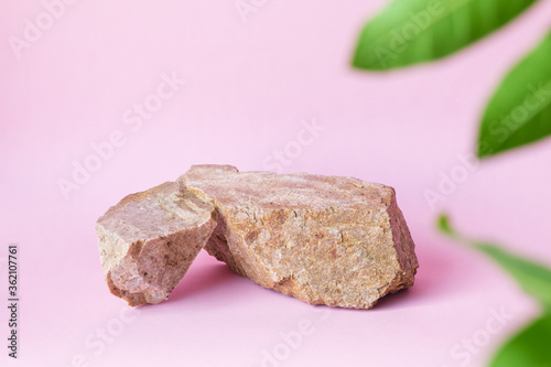 natural stones green leaves on a pastel pink background, space for product branding mockup