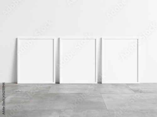 Three vertical empty white frame mock up on concrete floor. Blank frame mockup. 3d illustrations.