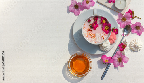 Moon milk Cup with rosehip flowers, honey and turmeric, flatlay on a white background