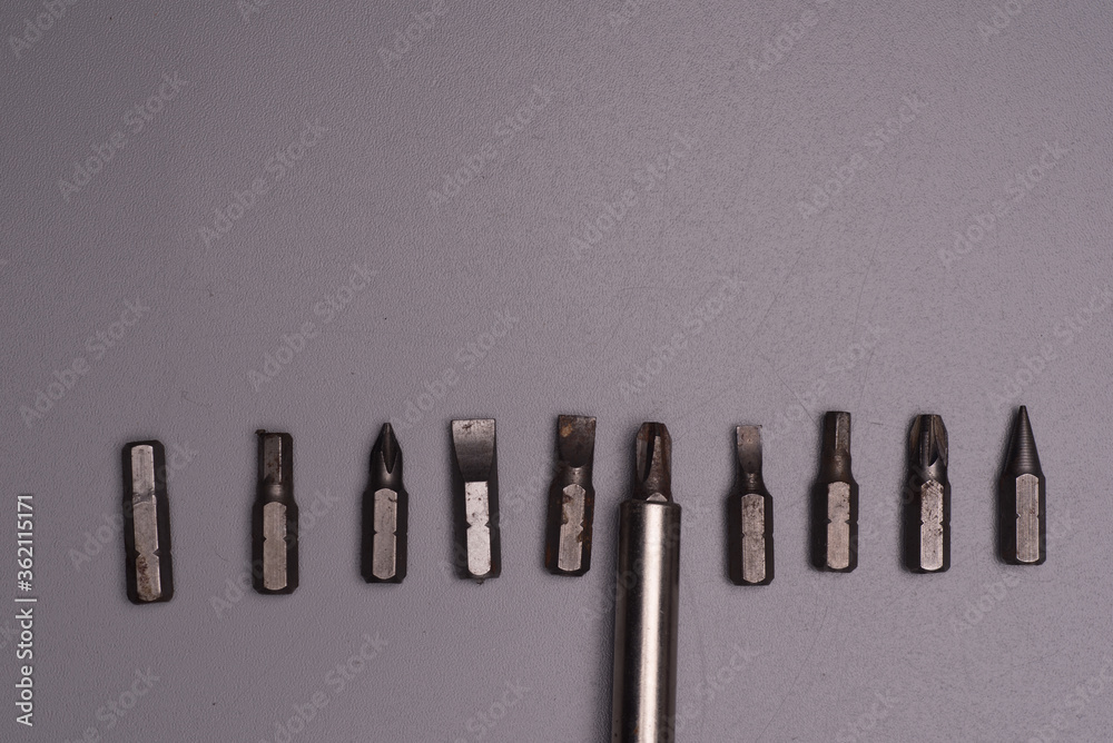 Interchangeable screwdriver bits over grey background Interchangeable screwdriver bits over grey background