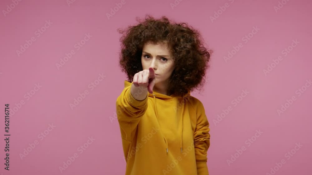 Hey you! Bossy angry girl afro hairstyle in hoodie pointing finger to camera, looking dissatisfied, choosing guilty, frowning and accusing with strict negative expression. indoor studio shot isolated Hey you! Bossy angry girl afro hairstyle in hoodie pointing finger to camera, looking dissatisfied, choosing guilty, frowning and accusing with strict negative expression. indoor studio shot isolated