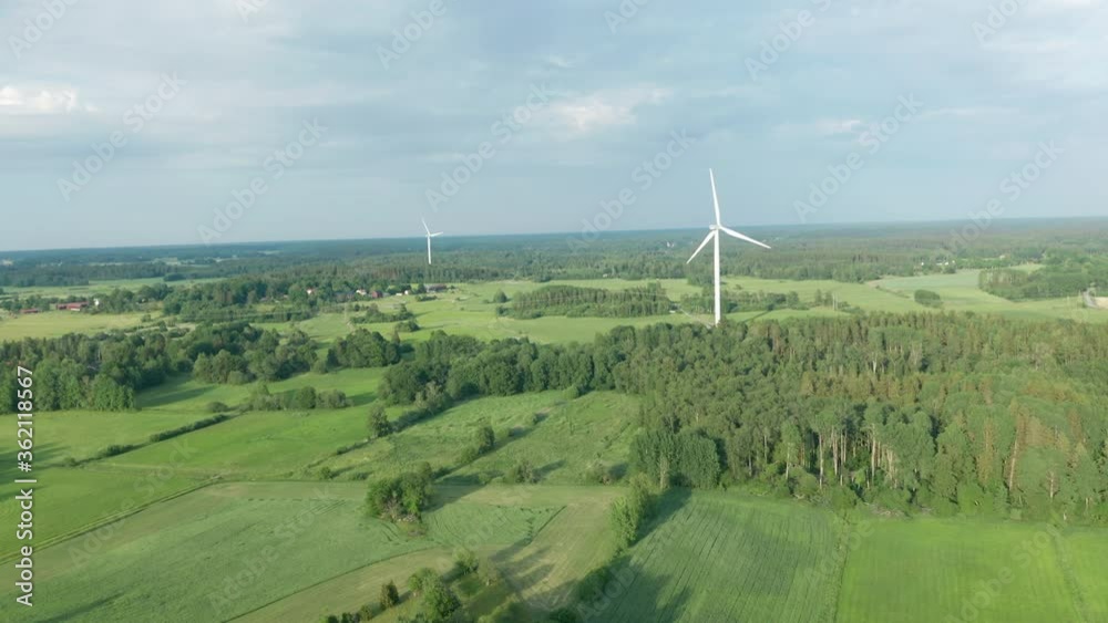 Aerial view flying toward wind turbines rotating providing clean renewable energy preventing global warming climate change Aerial view flying toward wind turbines rotating providing clean renewable energy preventing global warming climate change