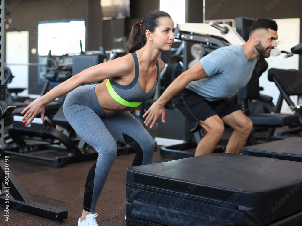 Fit couple doing jumping squats in crossfit gym. Fit couple doing jumping squats in crossfit gym.