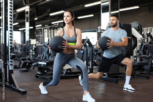 Attractive couple doing fitness with medcine ball at gym.