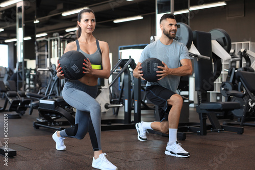 Attractive couple doing fitness with medcine ball at gym.