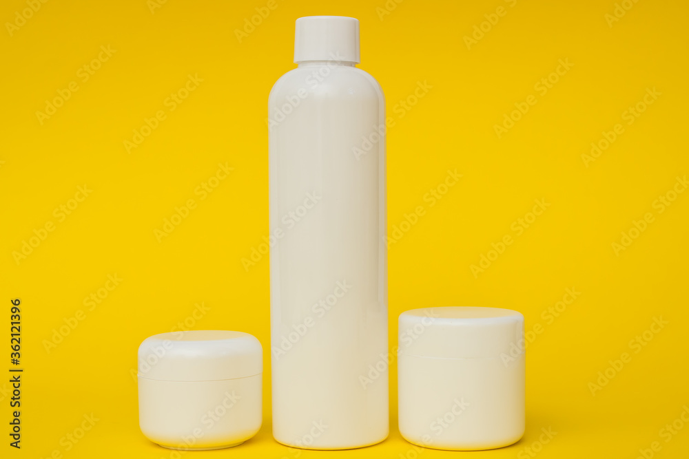 white plastic cosmetic jars and cream on a yellow background white plastic cosmetic jars and cream on a yellow background