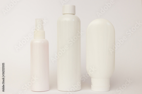 white plastic cosmetic jars and white open cream on a white background