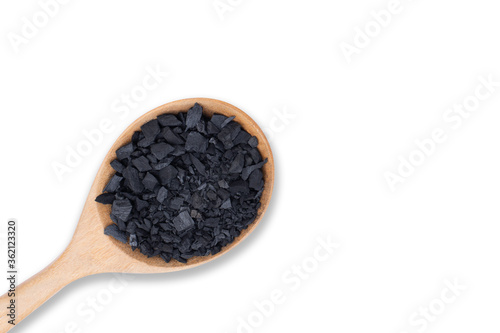 Natural broken black activated charcoal granular and powder in wooden spoon isolated on white background. Top view.