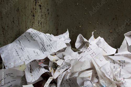 crumpled store receipts into street trash can under rain, consumerism society economy crisis concept