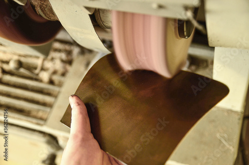 Buff by-hand grinding . Grinding coloured slice of cowhide with emery-wheel grinder. photo