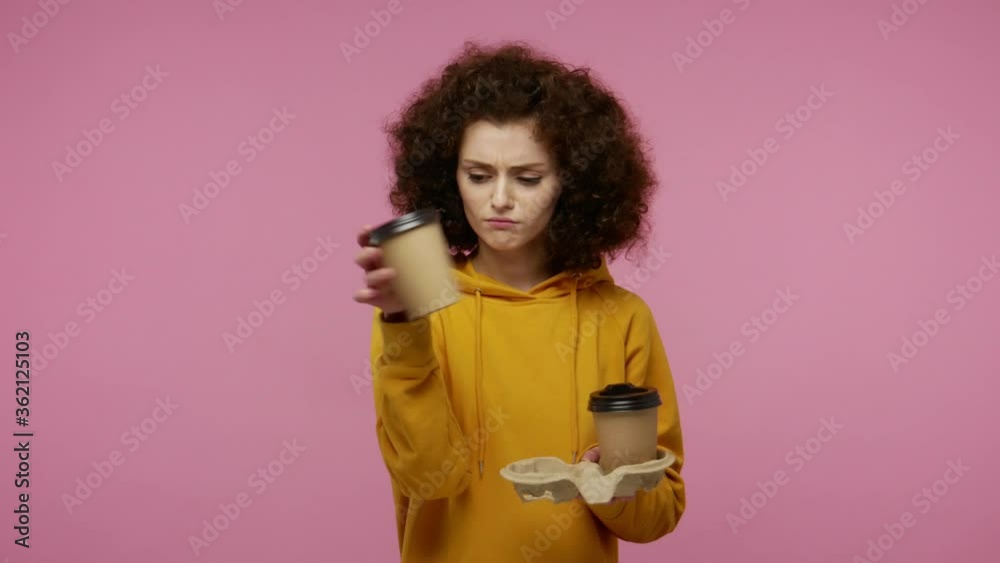 Very tired student girl afro hairstyle in hoodie drinking coffee two cups and looking at camera with disappointment, yawning feeling sleepy fatigued. indoor studio shot isolated on pink background Very tired student girl afro hairstyle in hoodie drinking coffee two cups and looking at camera with disappointment, yawning feeling sleepy fatigued. indoor studio shot isolated on pink background