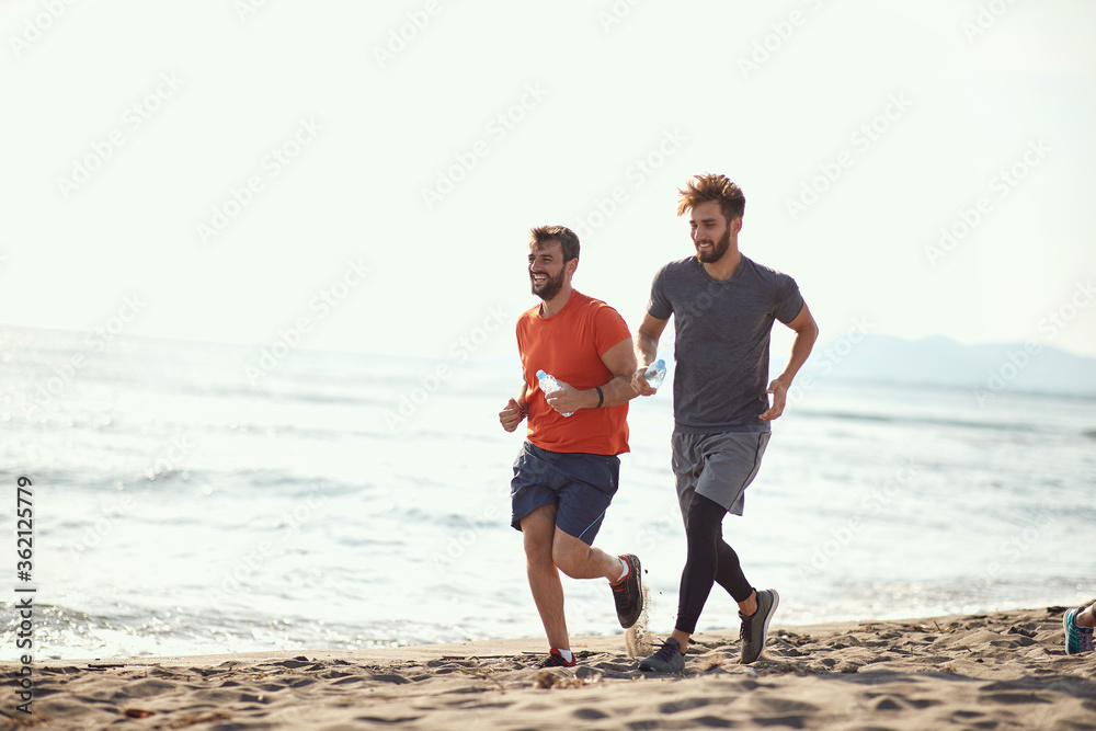 two guys running along the beach coast two guys running along the beach coast