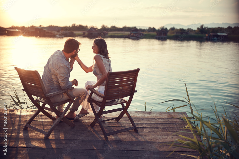 romantic caucasian couple in love sitting by the river.