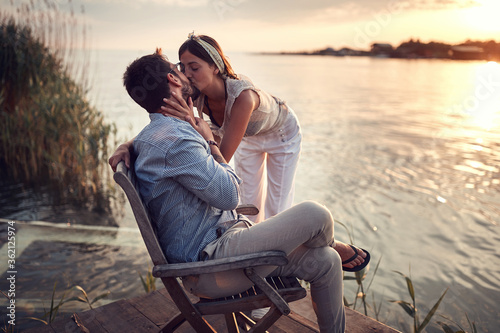 young beautiful  female kissing a man on the riverside at sunset