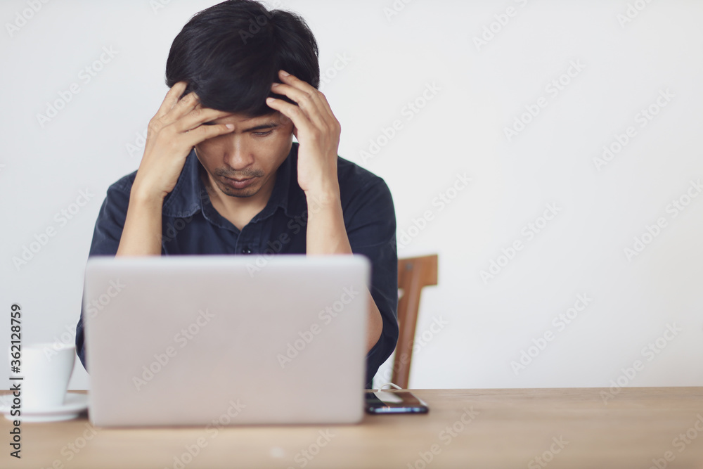 The man are stressed at work in the office. Asian businessman stressful and headache with laptop computer. Young male with headache at office, feeling sick at work. The man are stressed at work in the office. Asian businessman stressful and headache with laptop computer. Young male with headache at office, feeling sick at work.