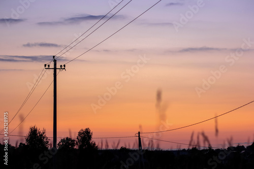 Silhouette of electric pole on meadow at sunset. Electricity, nature, sunset concept.