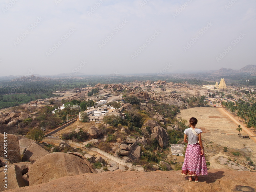 A woman is standing in a vantage point, looking at the ruins, Hampi, Karnataka, South India, India