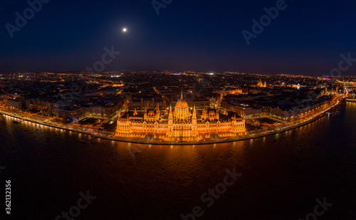 High angle panorama aerial drone shot of front facade of Hungarian Parliament with lights