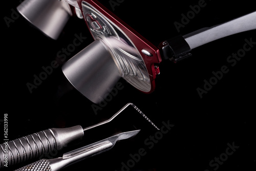 Closeup of professional dental tools. Periodontal probe, scalpel and magnifying glasses. photo