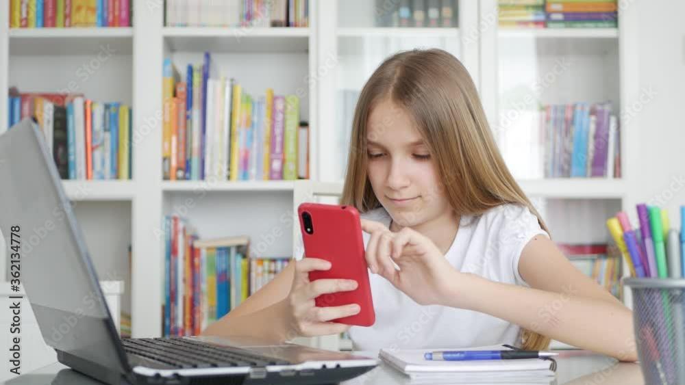 Kid Using Smartphone Studying in Video Conferencing, Child Learning, Writing in Library, Blonde Schoolgirl Chatting with Teacher at Home in Coronavirus Pandemic Crisis, Homeschooling, Online Education Kid Using Smartphone Studying in Video Conferencing, Child Learning, Writing in Library, Blonde Schoolgirl Chatting with Teacher at Home in Coronavirus Pandemic Crisis, Homeschooling, Online Education