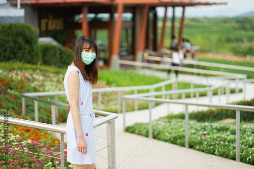 Young Asian woman wearing medical mask with classic 35mm rangefinder film camera. Holiday travel New normal after covid-19 concept.