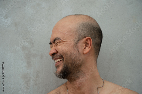 30-40s bald or skin head beard Japanese laughing happy man with grey cement background