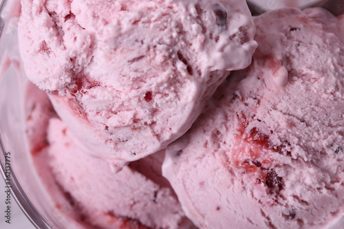 tasty cold melting strawberry and raspberry icecream in a glass container. close up shot.