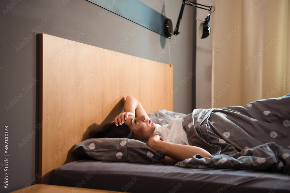 Side view of woman lying in bed and suffering from headache Side view of woman lying in bed and suffering from headache