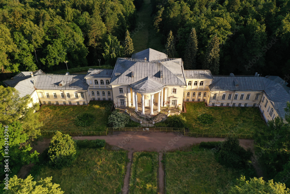 old white-stone manor in the forest at dawn filmed from a drone