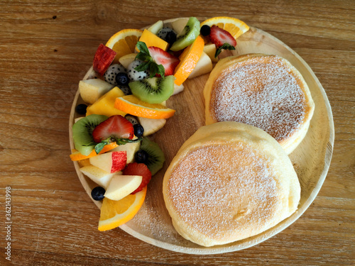 Pancakes with many fresh fruits on a wooden table
