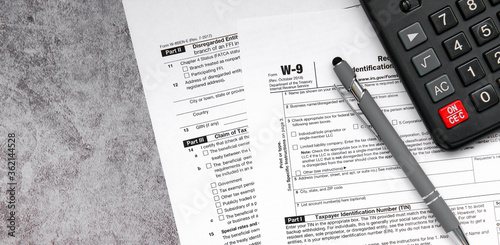 Tax relief and tax forms with a pen and a calculator to calculate taxes on a gray background