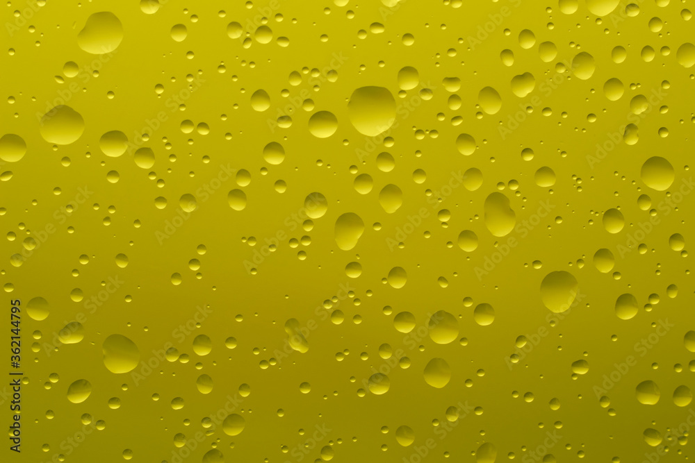 Drops of water of different shapes and sizes on a yellow background