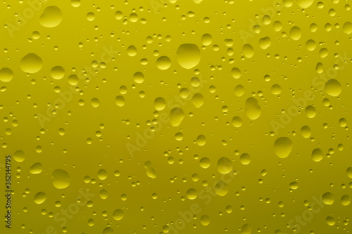 Drops of water of different shapes and sizes on a yellow background