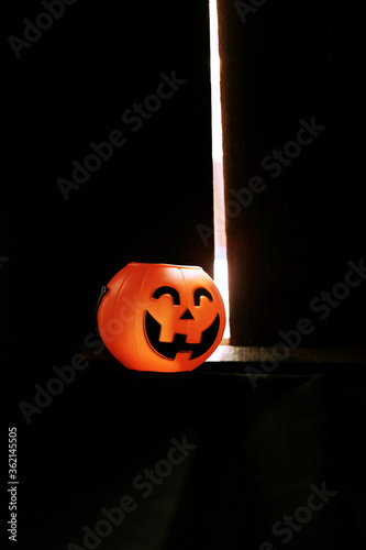 Smiling Halloween pumpkin head on black clothes in natural shadow and sunlight. Halloween holiday concept. photo