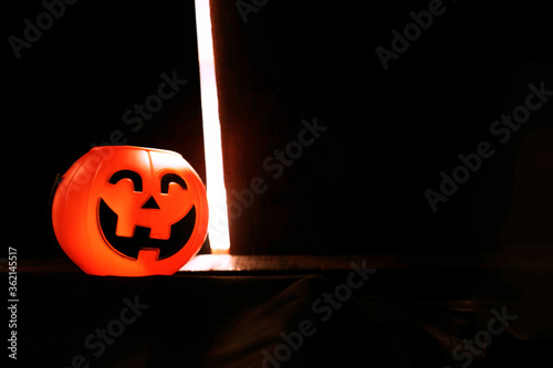 Smiling Halloween pumpkin head on black clothes in natural shadow and sunlight. Halloween holiday concept. photo