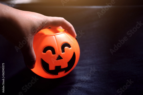 Scare hand holdung Halloween pumpkin head on black clothes in natural shadow and sunlight. Halloween holiday concept. photo