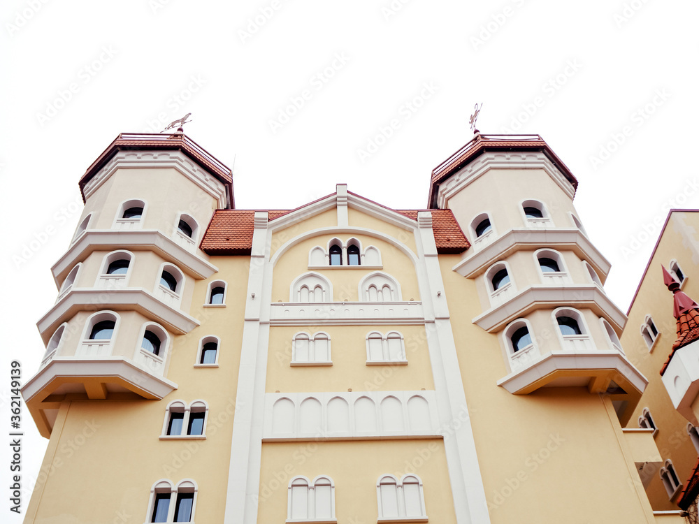 A yellow castle-style building with white decorative elements and a red tiled roof. Photo from bottom to top