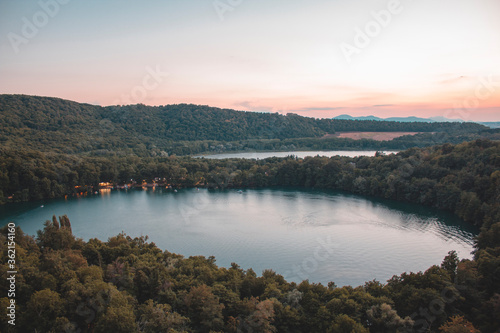 Monticchio lakes in the forest at the sunset. skyline of Monticchio lakes in the sunset. It is an amazing lake with church near them. There are two lakes in the forest on the hills