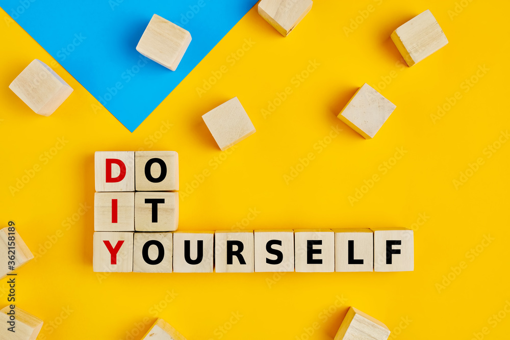 DIY and do it yourself words written on wooden blocks on yellow background DIY and do it yourself words written on wooden blocks on yellow background