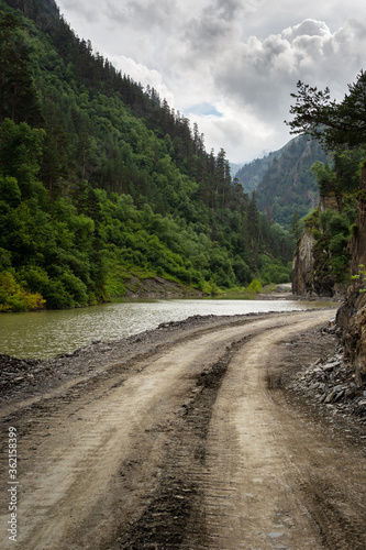 Dirt mountain road and river in the gorge among the mountains