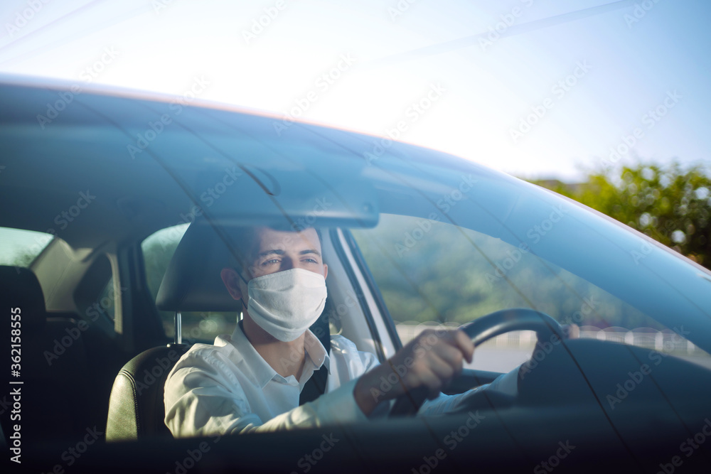 Man driving a car wearing on a medical mask during an epidemic, a driver- taxi in a mask. Covid-2019.